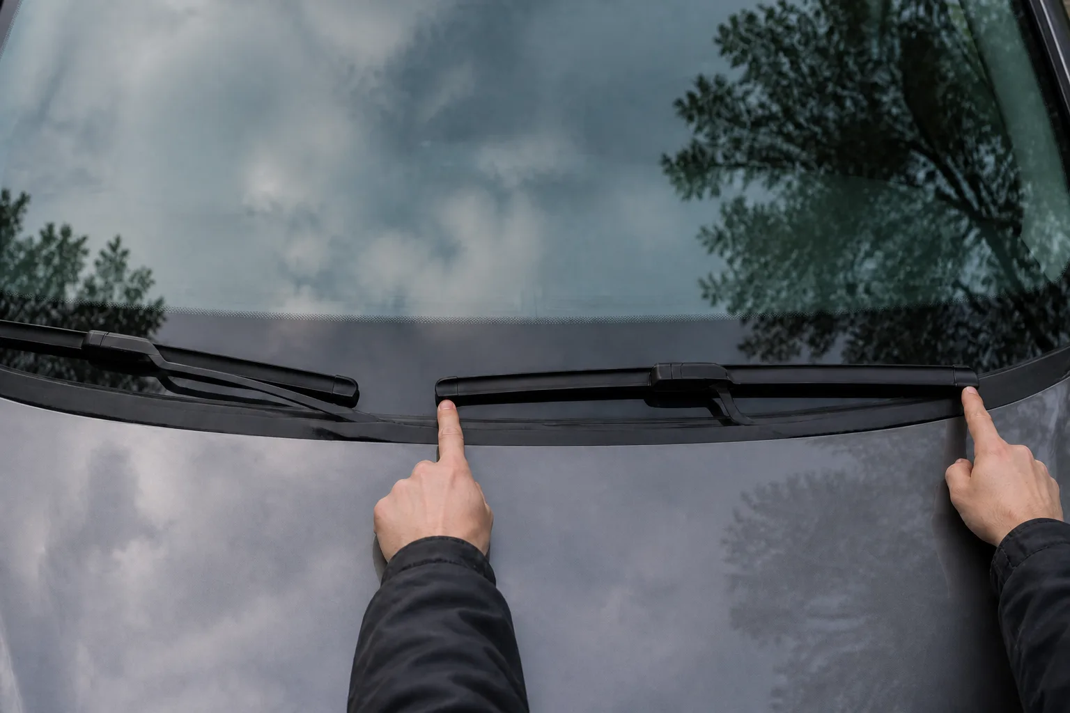 Two index fingers pointing at each end of a parked windscreen wiper blade to roughly gauge its length